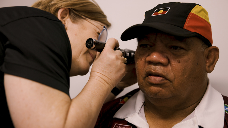 A client at a 715 health check having their ears checked by a doctor.