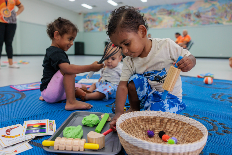 Children playing on a mat with toys