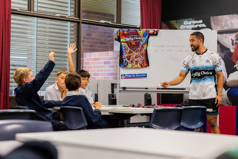 Deadly Choices Education Program - an educator at the front of a class room with a white board teaching a small group of students.