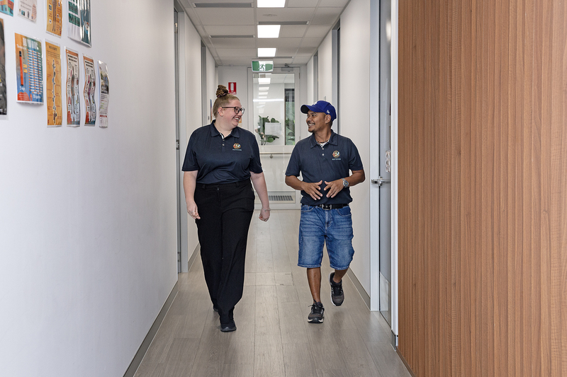 Photo of two staff members walking through the halls of a Moreton ATSICHS clinic for our Jobs at Moreton ATSICHS page.