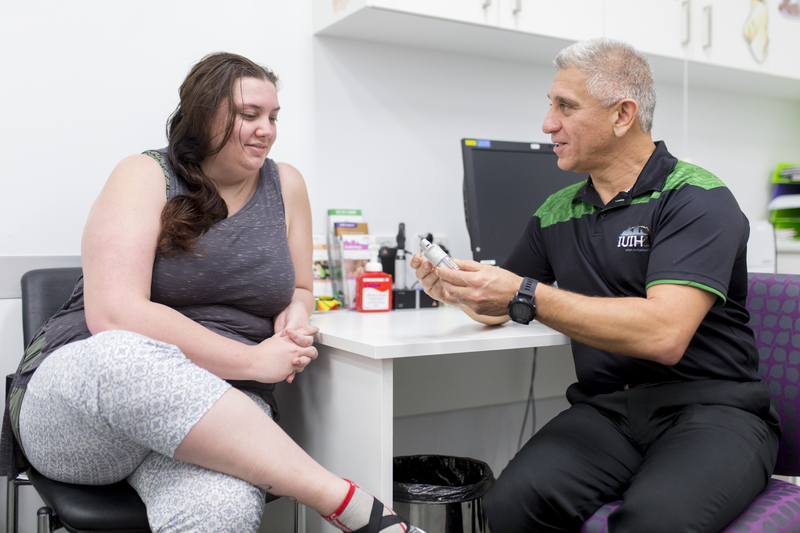 A pharmacist yarning with a client about medication in a clinical setting.