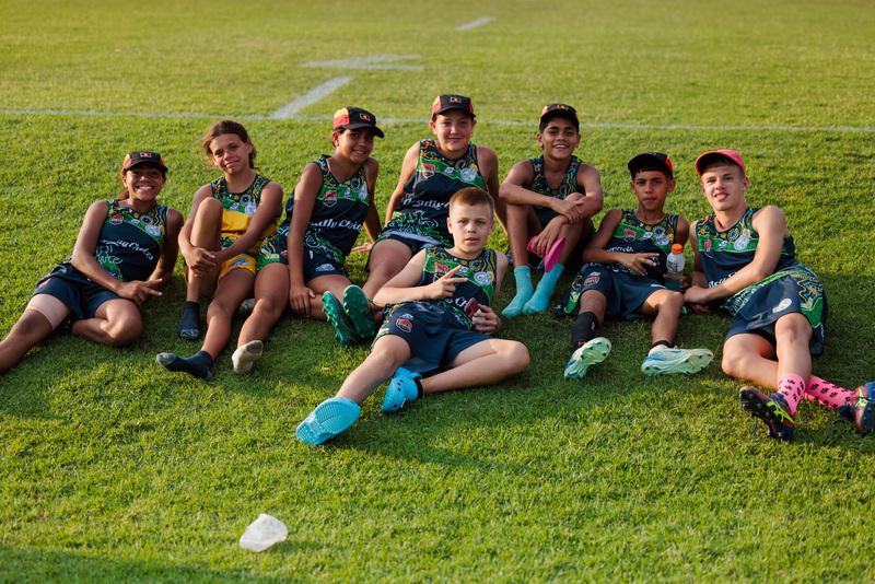 A group of deadly youth sports players relaxing on grass wearing their deadly jerseys.